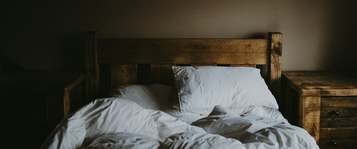 a bed made out of wood with white linen